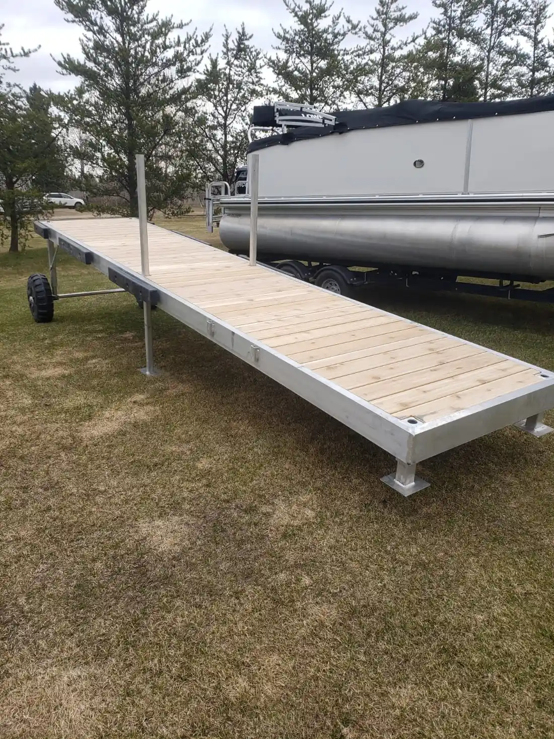 Long aluminum dock frame with cedar planks staged beside pontoon boat