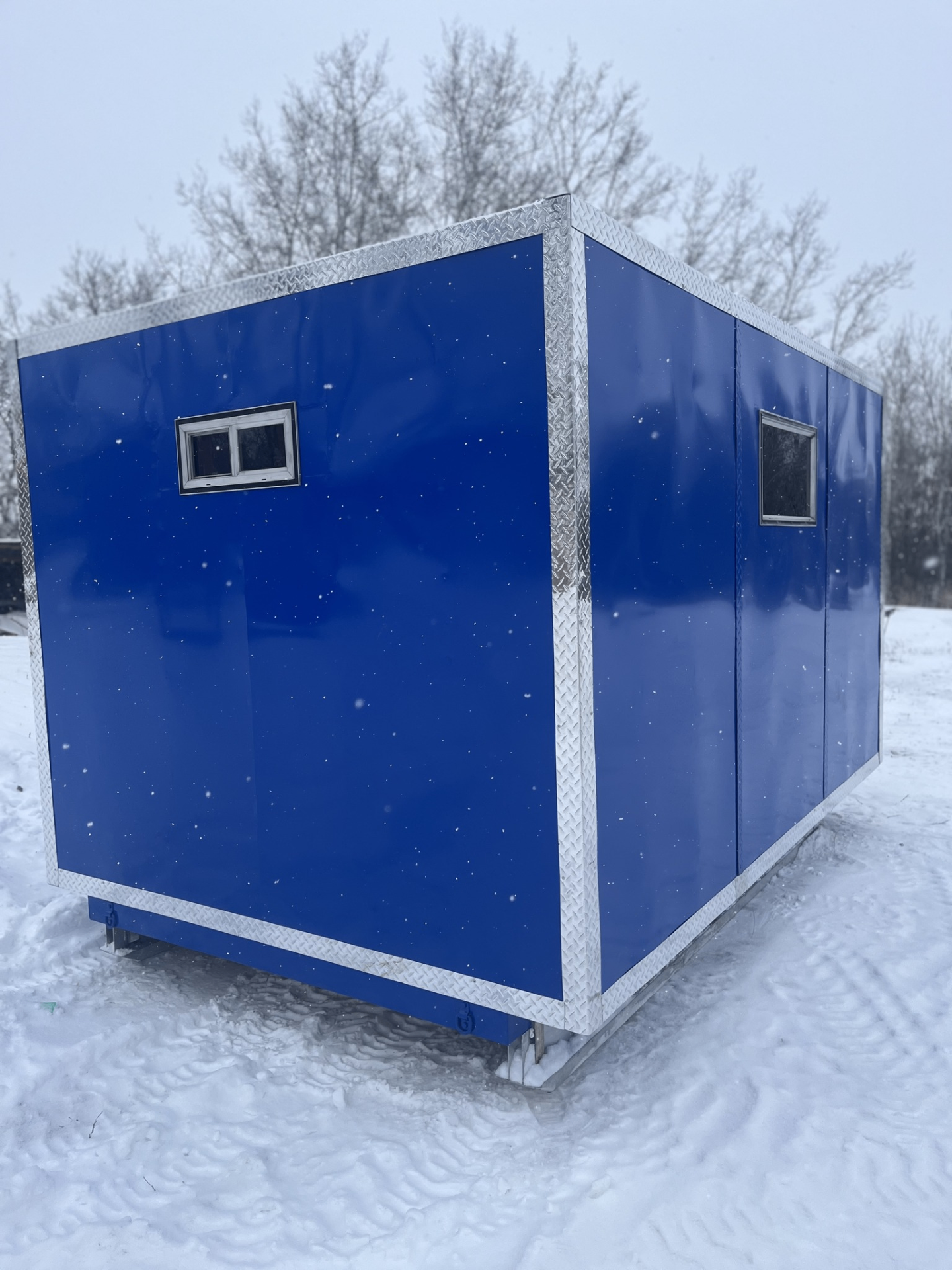 Side profile of blue aluminum ice shack with windows
