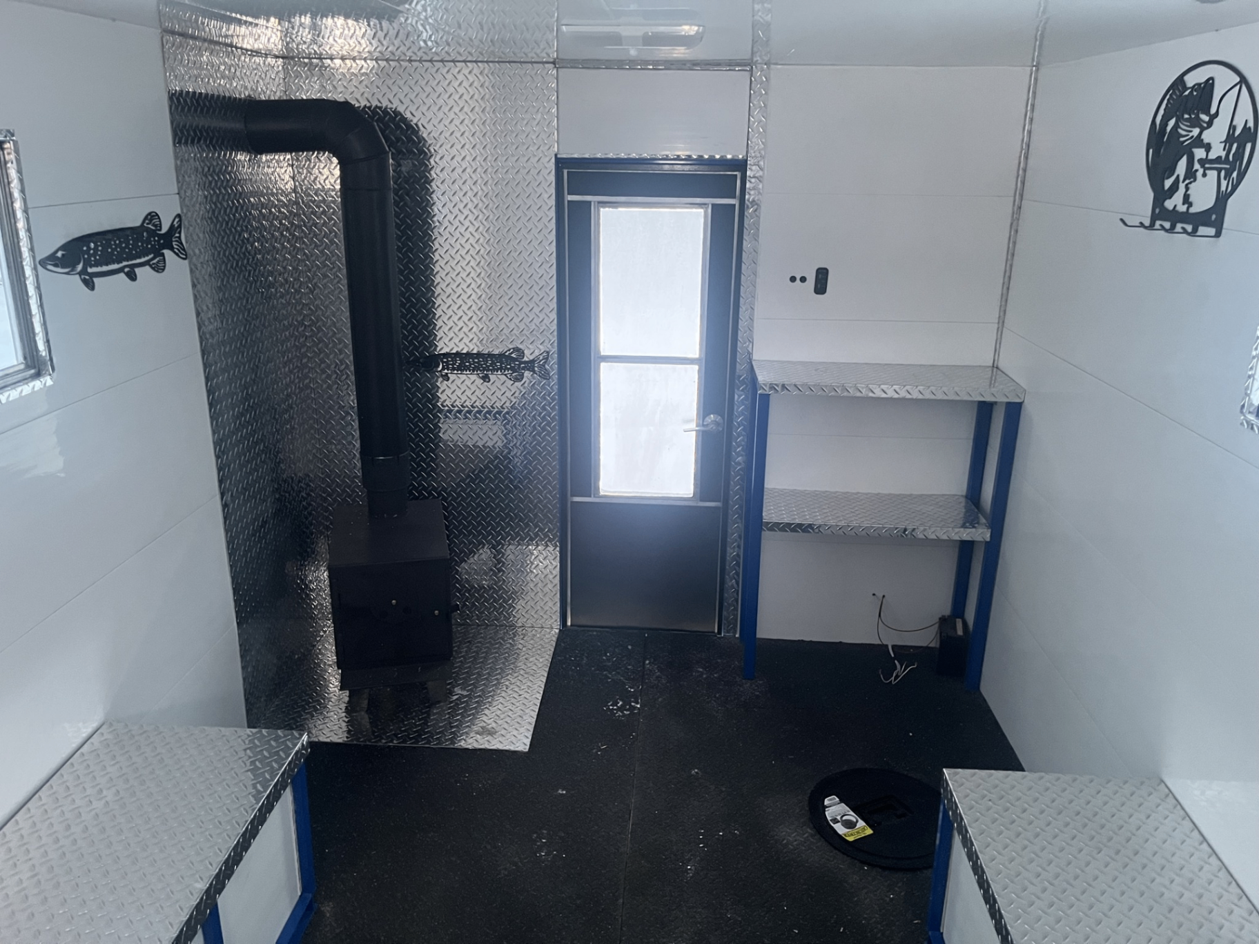 Interior of ice shack with wood stove, diamond plate, and shelving