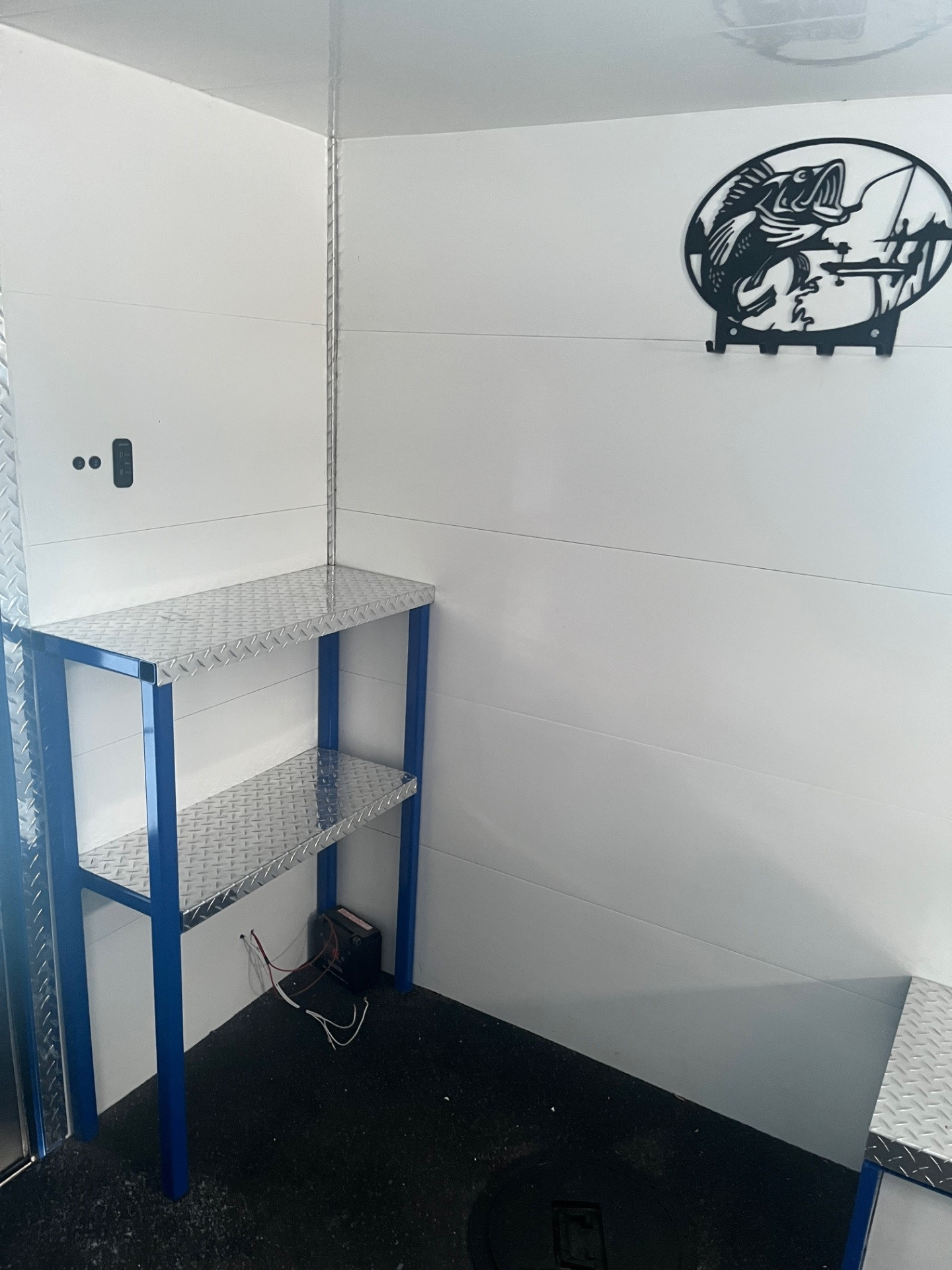 Interior corner with blue-framed diamond-plate shelving and fish wall art